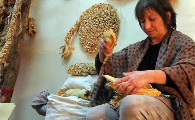 Artxibiko argazkian, Lola Altolagirre artoa prestatzen, horren lastoarekin alfonbrak egiteko.