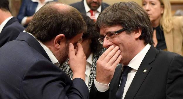 El gesto. Carles Puigdemont y Oriol Junqueras dialogan tapándose la boca para que nadie pueda leer sus labios./ R. C.