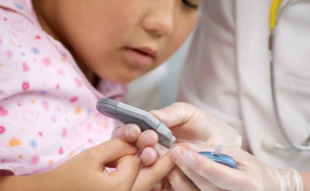 Un médico mide el nivel de glucosa a una niña. /