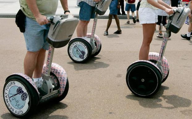 Varias personas montan un patinete eléctrico. /Jason Reed (Reuters)