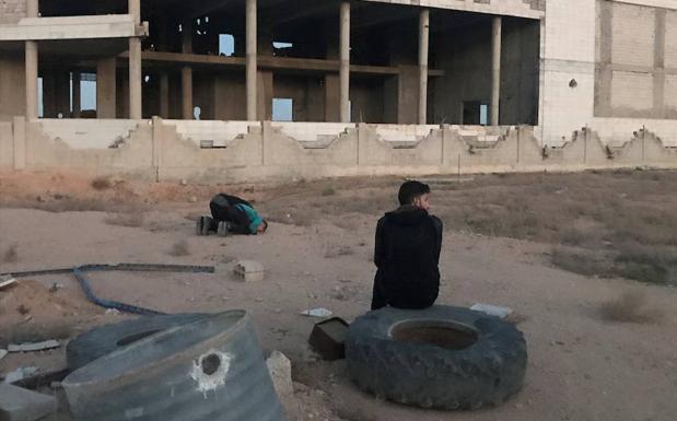 Dos hombres rezan mientras esperan la llegada del resto de evacuados civiles y combatientes de Faylaq al-Rahman, a las afueras de Damasco (Siria), para salir de la población de Duma hacia Idlib. /Mohamed Badra (Efe)