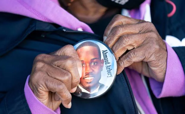 A woman wears a badge with the face of Ahmaud Arbery during a protest in front of the court that was trying the defendants. 