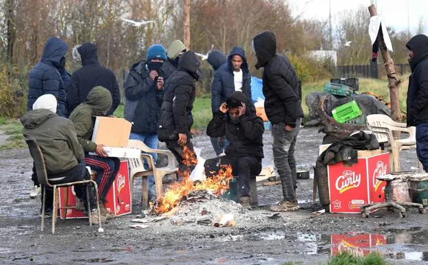 More than a dozen migrants try to keep warm around a small bonfire in Pas de Calais, France.