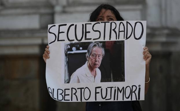 A woman holds up a poster calling for Fujimori's release. 