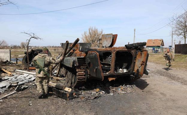 A Ukrainian soldier examines the remains of a Russian armored vehicle, destroyed north of kyiv.