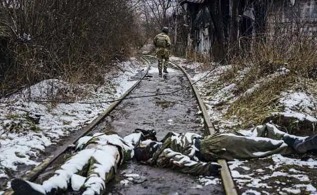 A Ukrainian soldier walks along a railway next to the bodies of dead Russian soldiers on the outskirts of Irpin, Ukraine, on March 1, 2022.