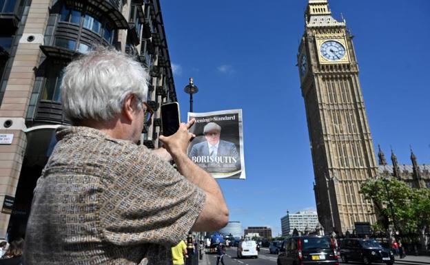 A citizen photographs a newspaper with Johnson's resignation and Big Ben in the background. 