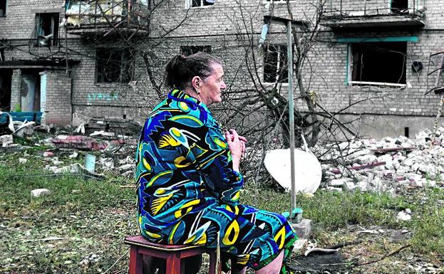 A woman sits in front of the ruins of a building in Chasiv Ya.