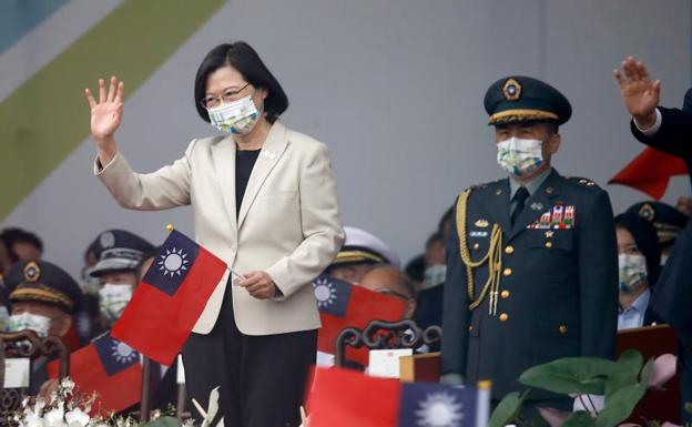 Taiwanese President Tsai Ing-wen holds a Taiwanese flag as it waves during the Taiwan National Day celebrations in front of the Presidential Palace in Taipei. 