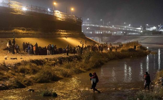 Central American migrants gather on the US bank of the Rio Grande to cross the wall. 