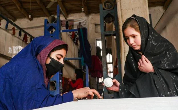 Afghan women weave carpets in a workshop in Herat province. 