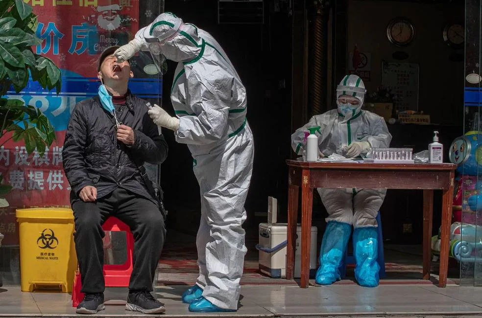 A medical worker in full protective gear tests a man for symptoms of Covid-19 on a street in Wuhan, China, on April 1, 2020. 